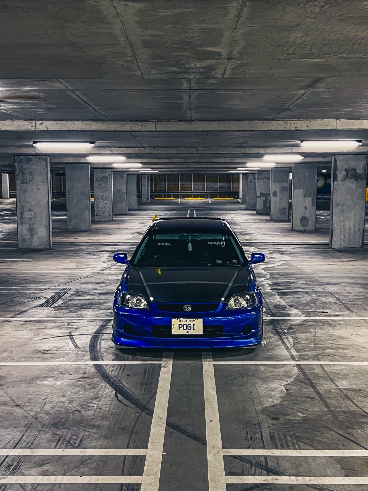 Front view of the blue Civic with the POGI plate in a concrete car park